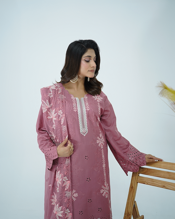 A model wearing Amzoclothing’s Dusty Mauve 3-piece cotton suit with boring embroidery, laser cutwork sleeves, cutwork trousers, and embroidered chiffon dupatta – Eid festive wear 2025.