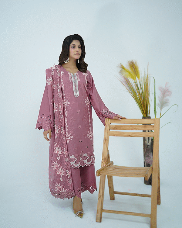 A model wearing Amzoclothing’s Dusty Mauve 3-piece cotton suit with boring embroidery, laser cutwork sleeves, cutwork trousers, and embroidered chiffon dupatta – Eid festive wear 2025.