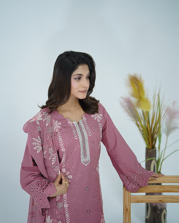 A model wearing Amzoclothing’s Dusty Mauve 3-piece cotton suit with boring embroidery, laser cutwork sleeves, cutwork trousers, and embroidered chiffon dupatta – Eid festive wear 2025.