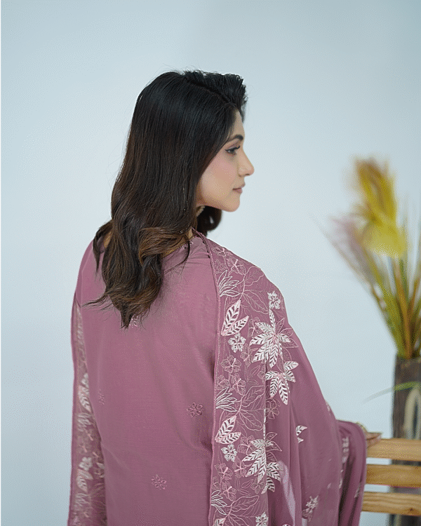 A model wearing Amzoclothing’s Dusty Mauve 3-piece cotton suit with boring embroidery, laser cutwork sleeves, cutwork trousers, and embroidered chiffon dupatta – Eid festive wear 2025.