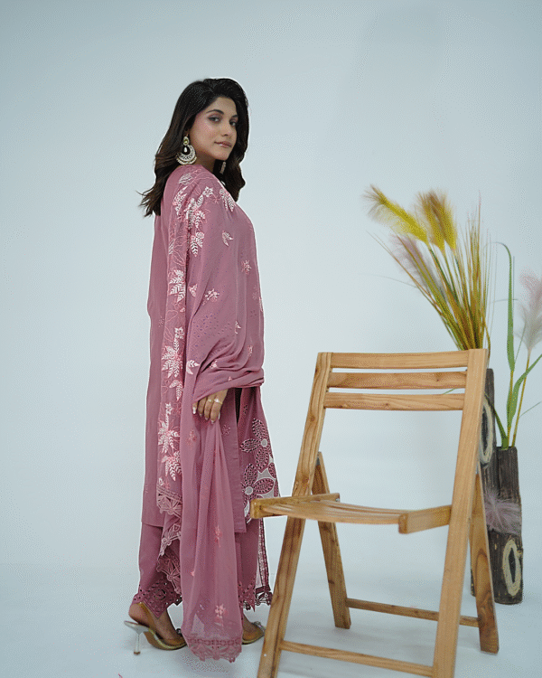 A model wearing Amzoclothing’s Dusty Mauve 3-piece cotton suit with boring embroidery, laser cutwork sleeves, cutwork trousers, and embroidered chiffon dupatta – Eid festive wear 2025.