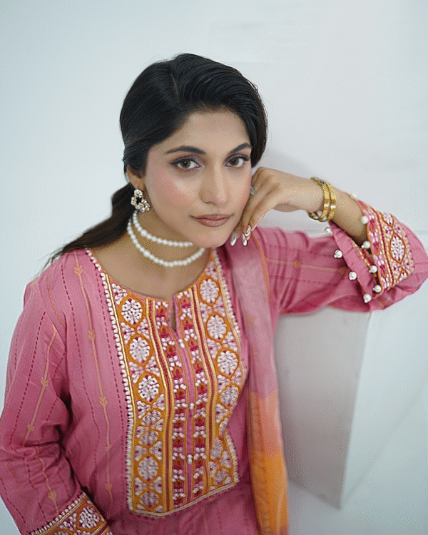 Model in pink embroidered lawn Eid dress with pearl details, white sharara pants, and printed net dupatta – Amzoclothing Eid 2025.