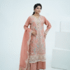 A model wearing a peach embroidered lawn Eid dress with intricate boring design and organza border, paired with a cotton net dupatta with embroidered borders – Amzoclothing festive collection.