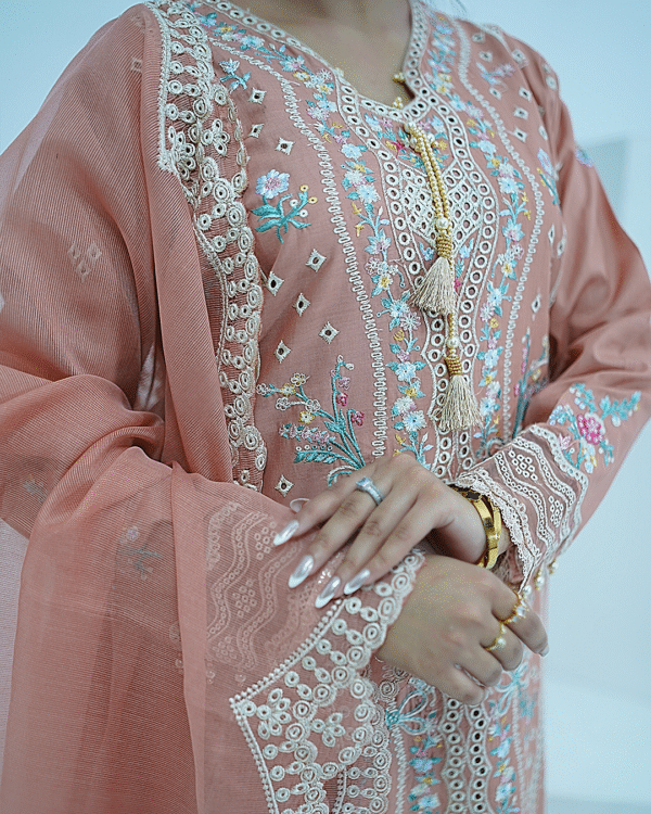 A model wearing a peach embroidered lawn Eid dress with intricate boring design and organza border, paired with a cotton net dupatta with embroidered borders – Amzoclothing festive collection.