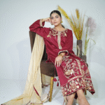A model wearing a maroon elegance gold sequin embroidered festive shirt with masuri gold dupatta featuring traditional tassel hangings – Eid/wedding outfit by Amzoclothing.