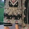 Woman wearing an elegant black embroidered long dress with beige and pink floral detailing, styled with gold clutch and pink heels